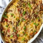 Ground Beef Hashbrown Casserole cooked in dish with green onion topping.