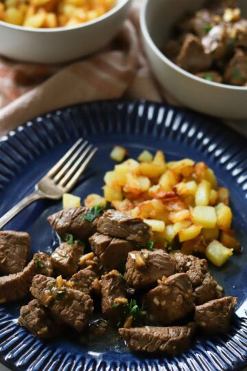 Garlic butter steak bites and potatoes on plate.