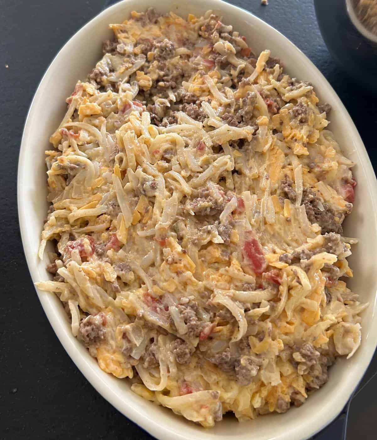 Hamburger hashbrown hotdish ingredients in casserole dish.