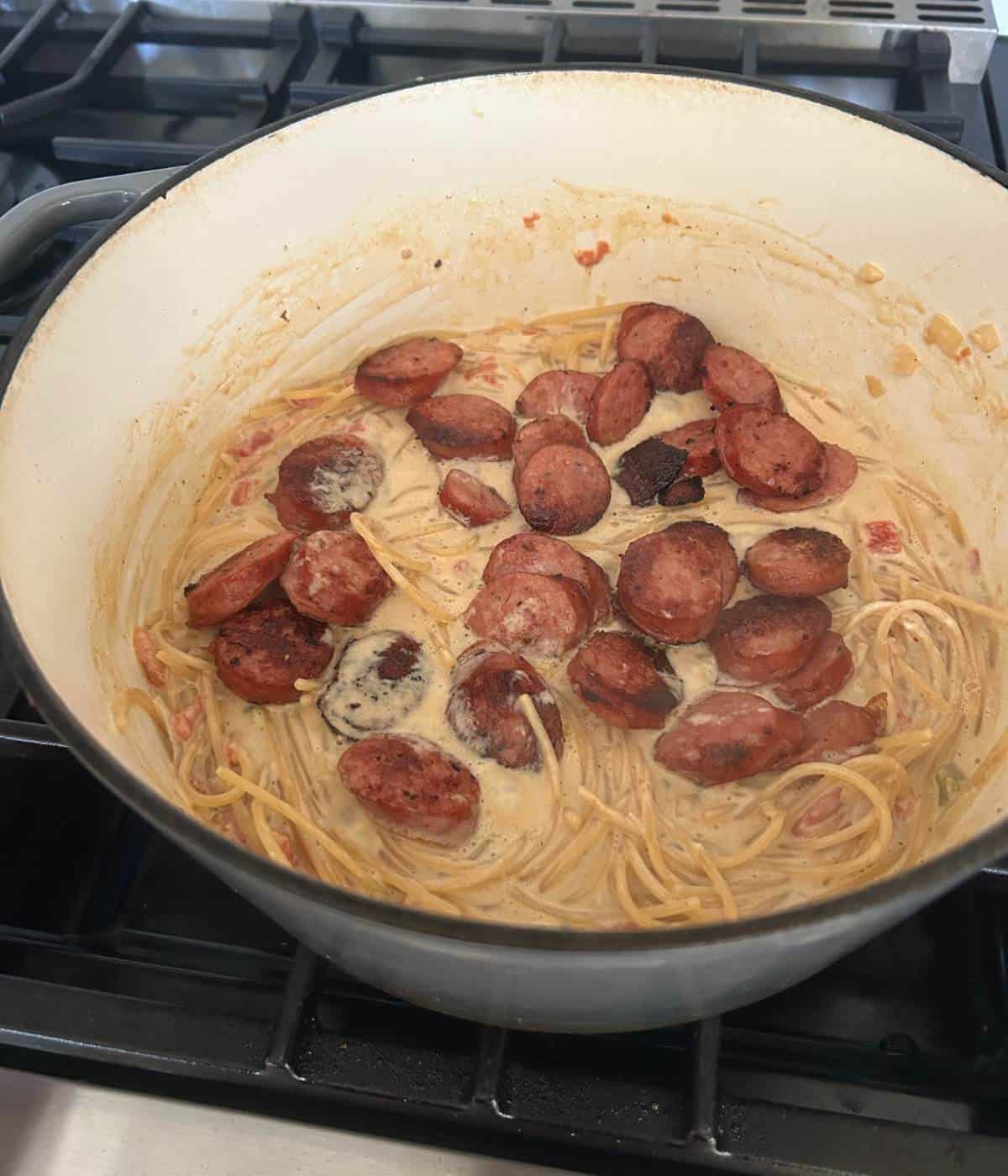 Creamy spaghetti with andouille sausage in pot.