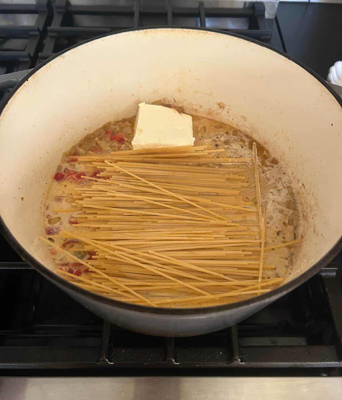 Spaghetti with cream cheese and sauce in pot.