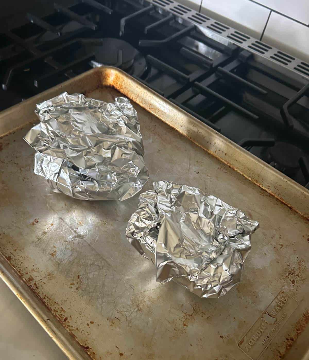Squash wrapped in foil on cookie sheet.