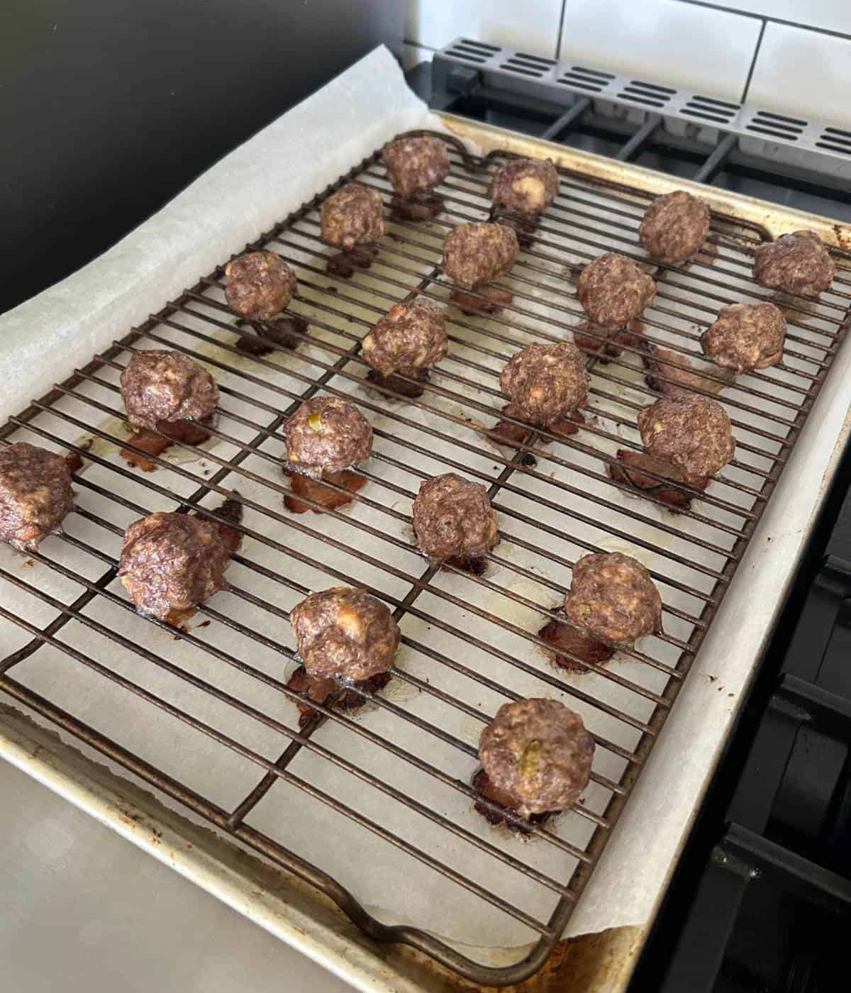 Baked meatballs on cookie sheet.