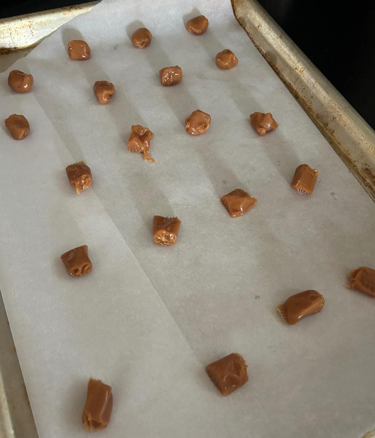 Caramels sliced in half on parchment paper.