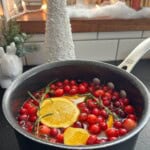 Simmer pot with cranberries, orange, apple cider, and rosemary.