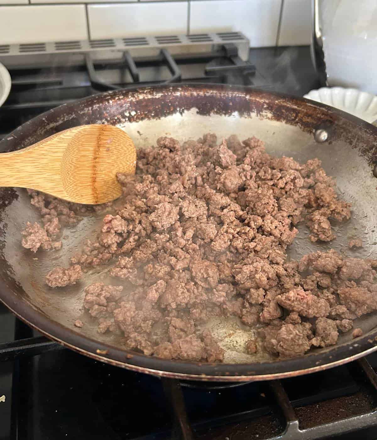 Ground beef cooking in skillet.