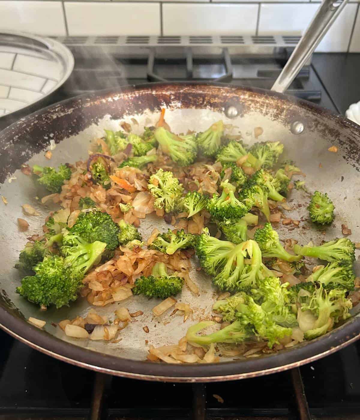 Broccoli, slaw and onions cooking in skillet.