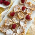 Lemon curd tarts on platter with raspberries.