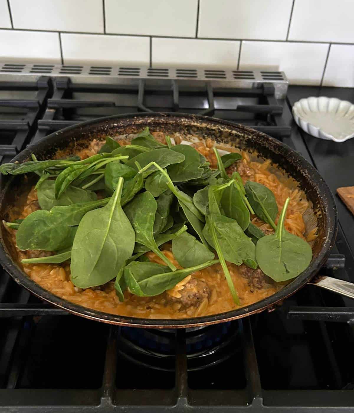 Adding baby spinach to pan.