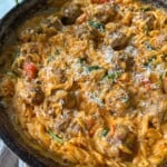 Cheesy orzo and meatballs in skillet.