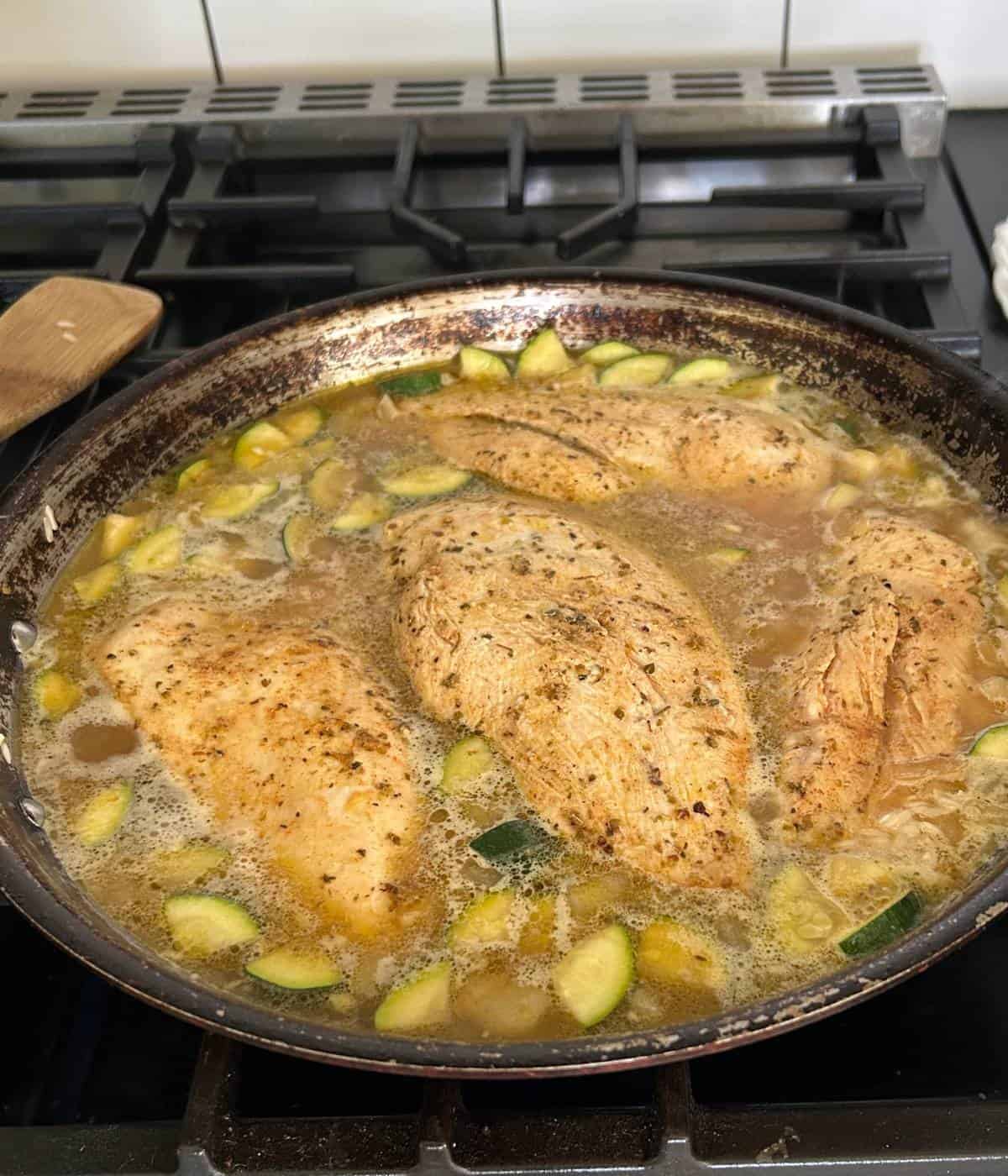One pot chicken cooking in skillet.