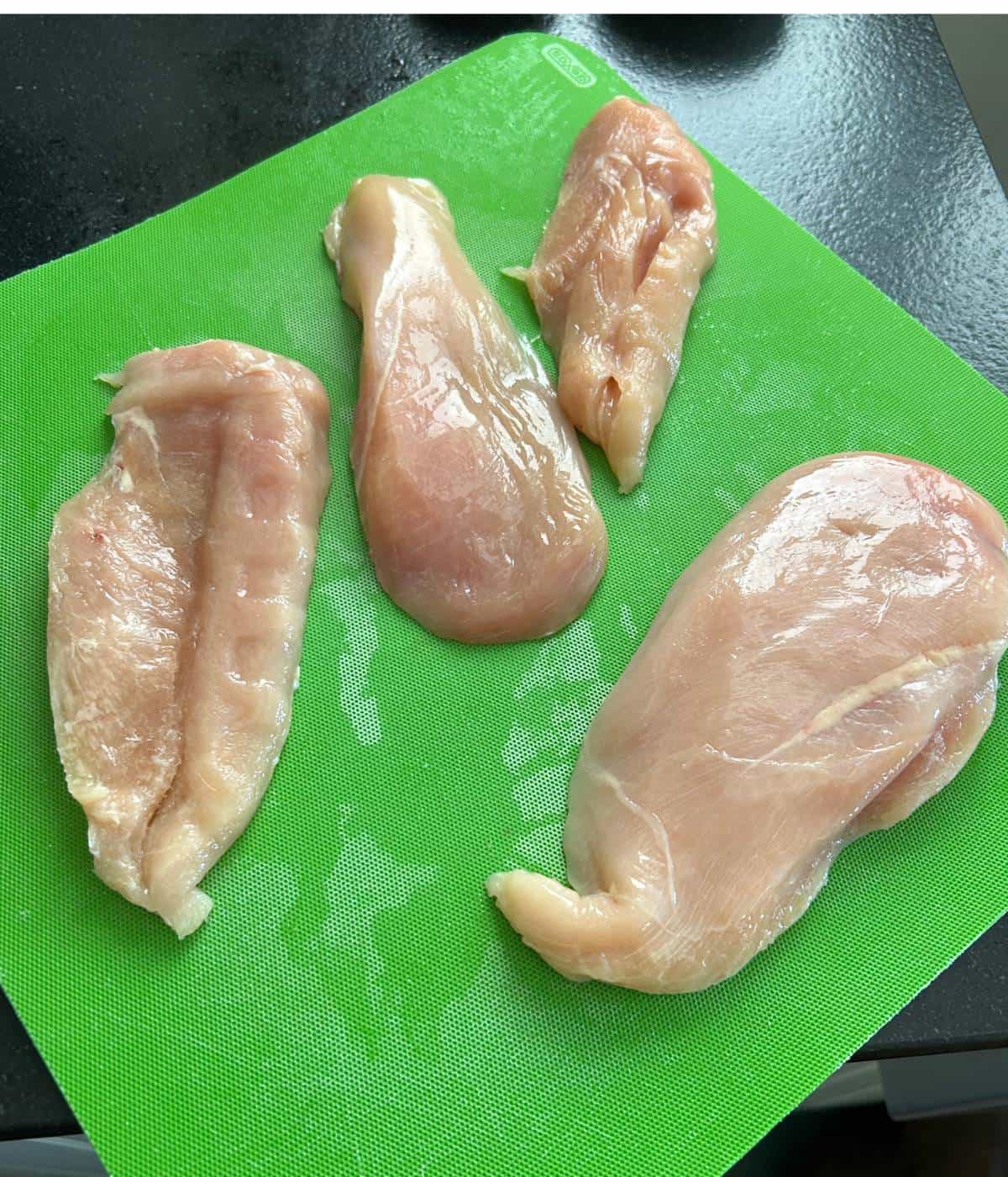 Chicken cutlets on cutting board.