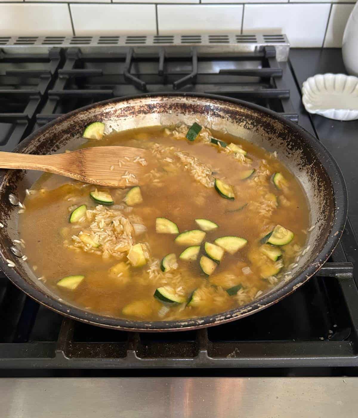 Rice zucchini and onions in skillet.