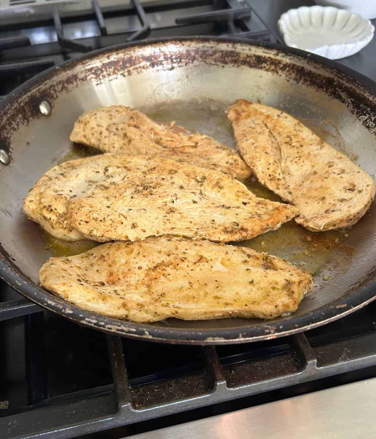 Sautéed chicken breast in pan.