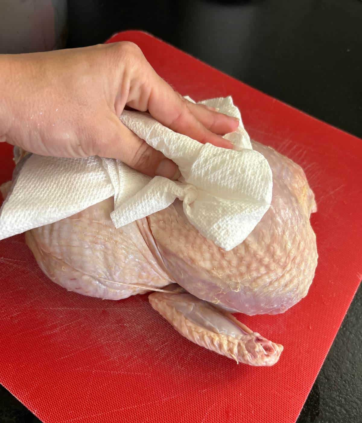 Raw chicken being dabbed with paper towels.