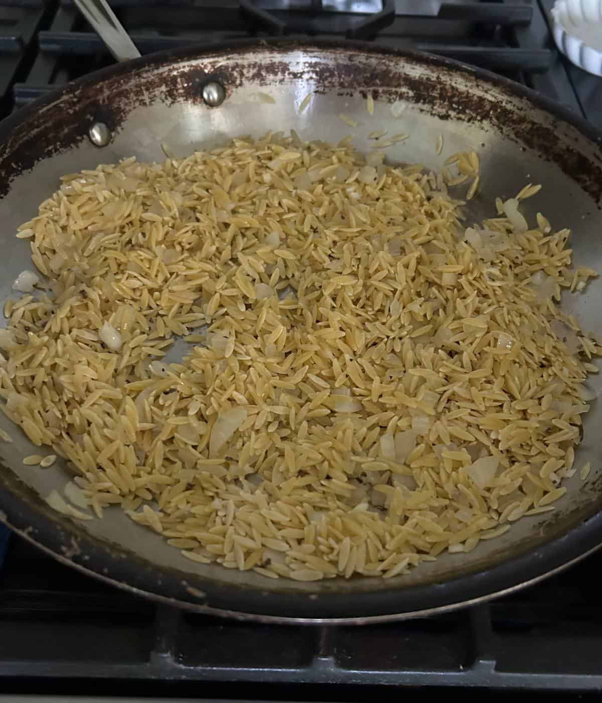 Toasted orzo in skillet.