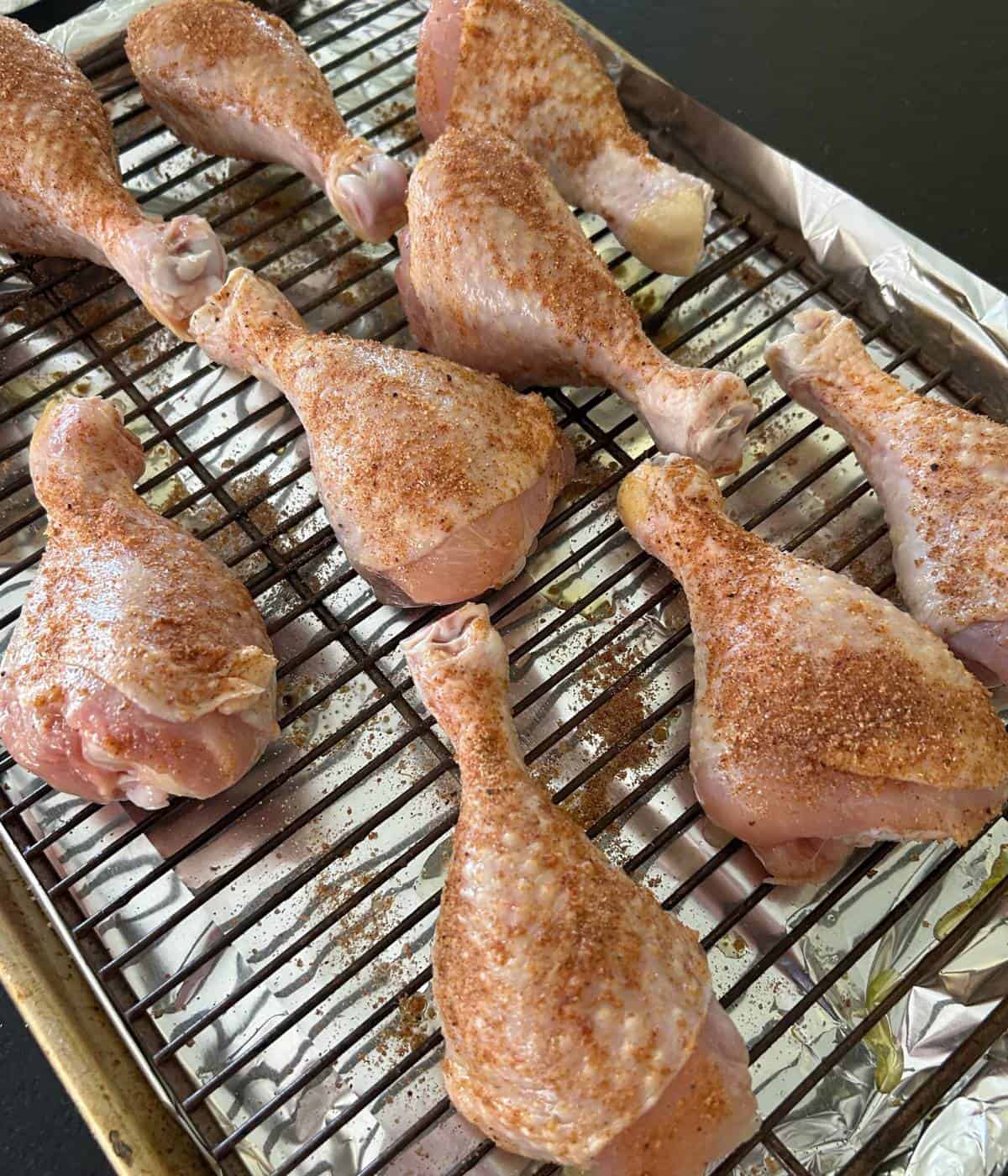 Seasoned bbq chicken drumsticks on rack.