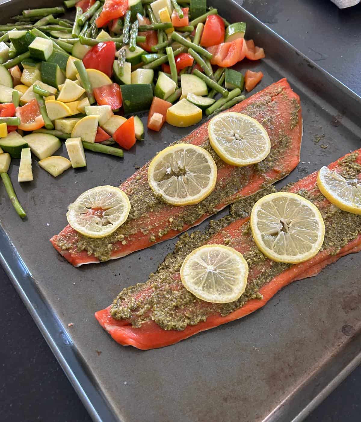 Salmon with pesto sauce and vegetables ready for the oven.