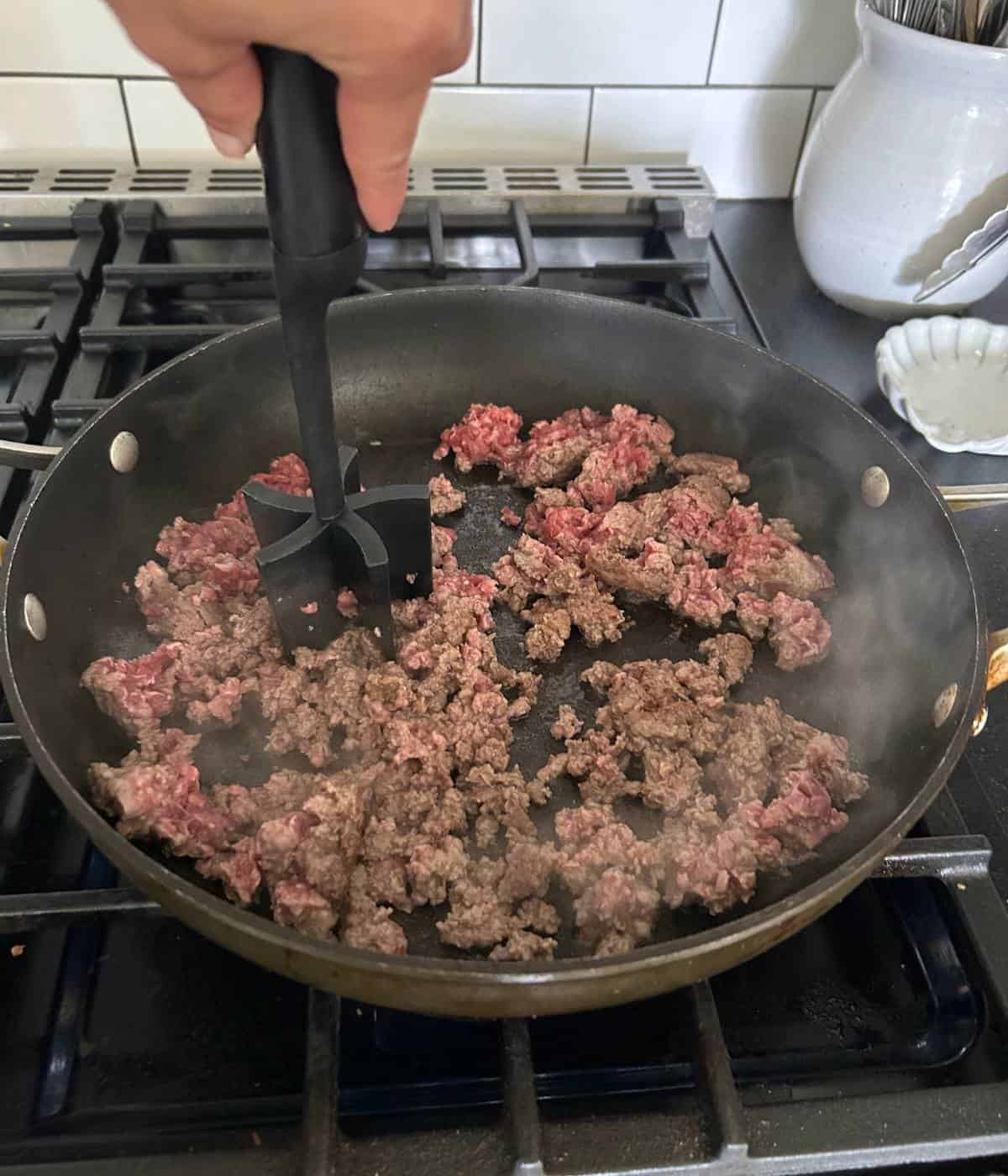 Ground beef cooking in skillet.