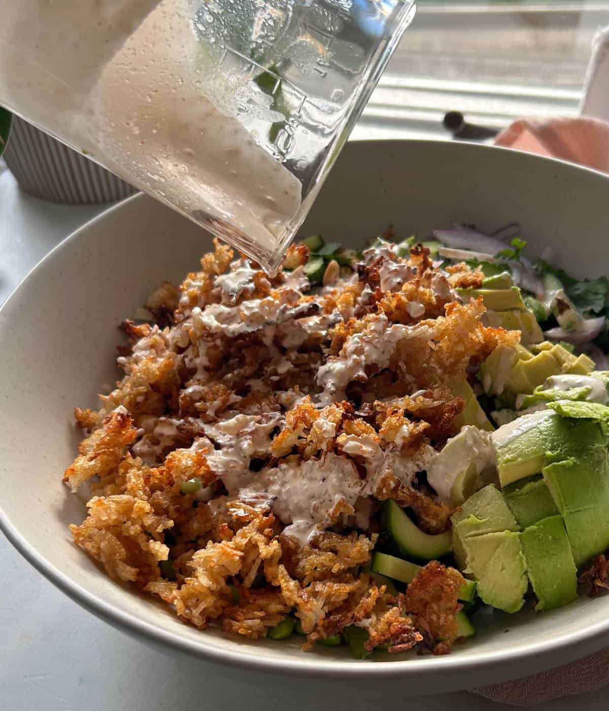 Pouring sriracha mayo dressing over rice salad.