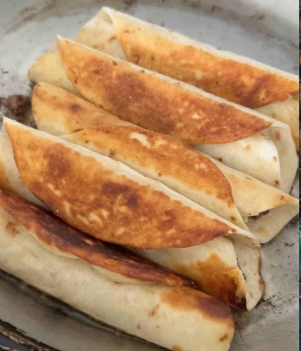 Beef taquitos in skillet.