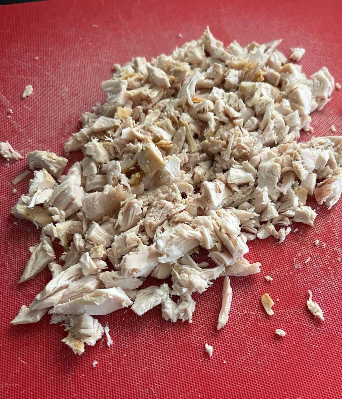 Chopped up chicken on cutting board.