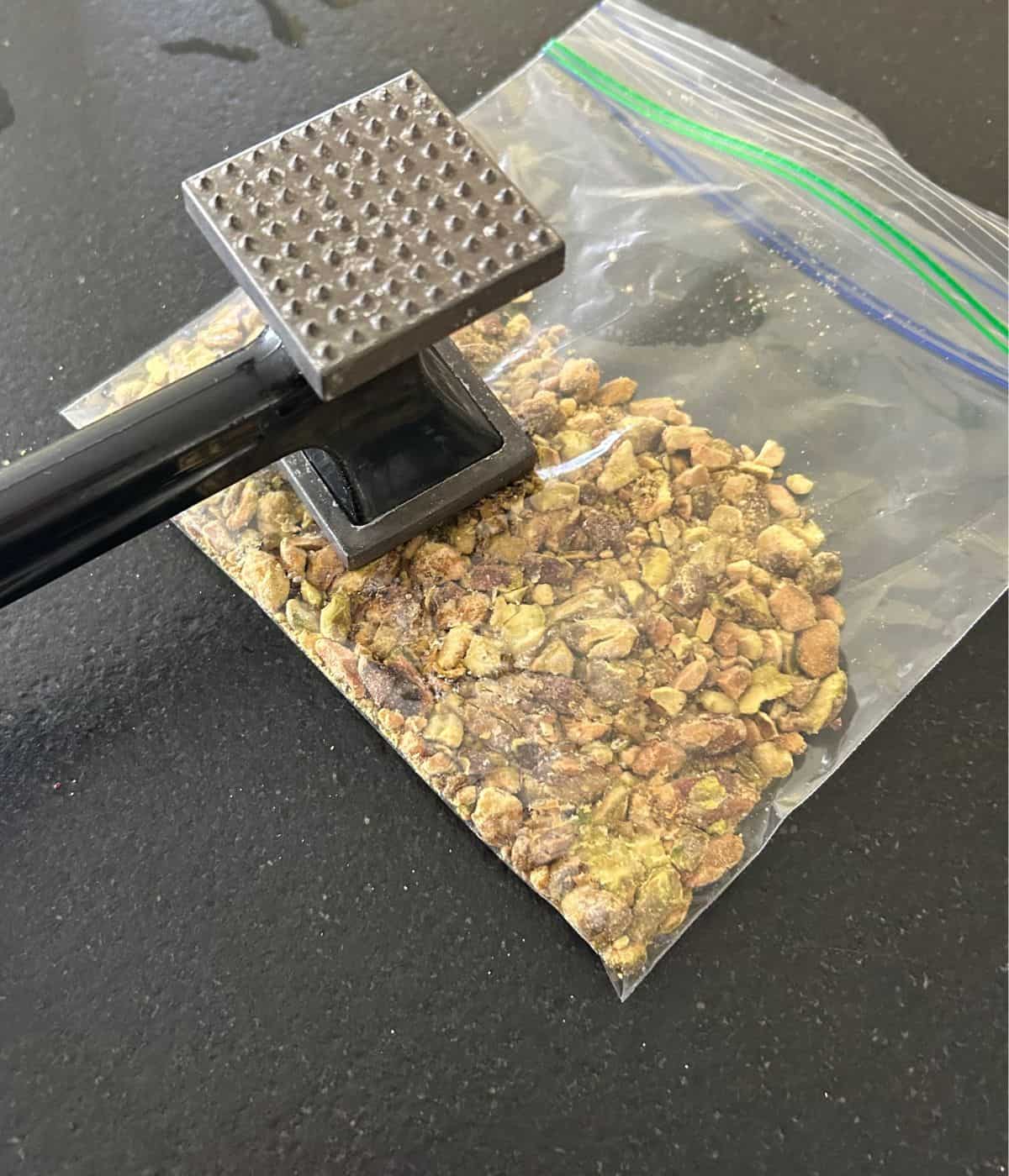 Crushing pistachios with mallet.