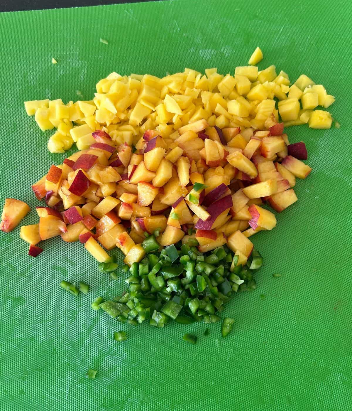 Diced peaches, mango, and jalapeno on cutting board.
