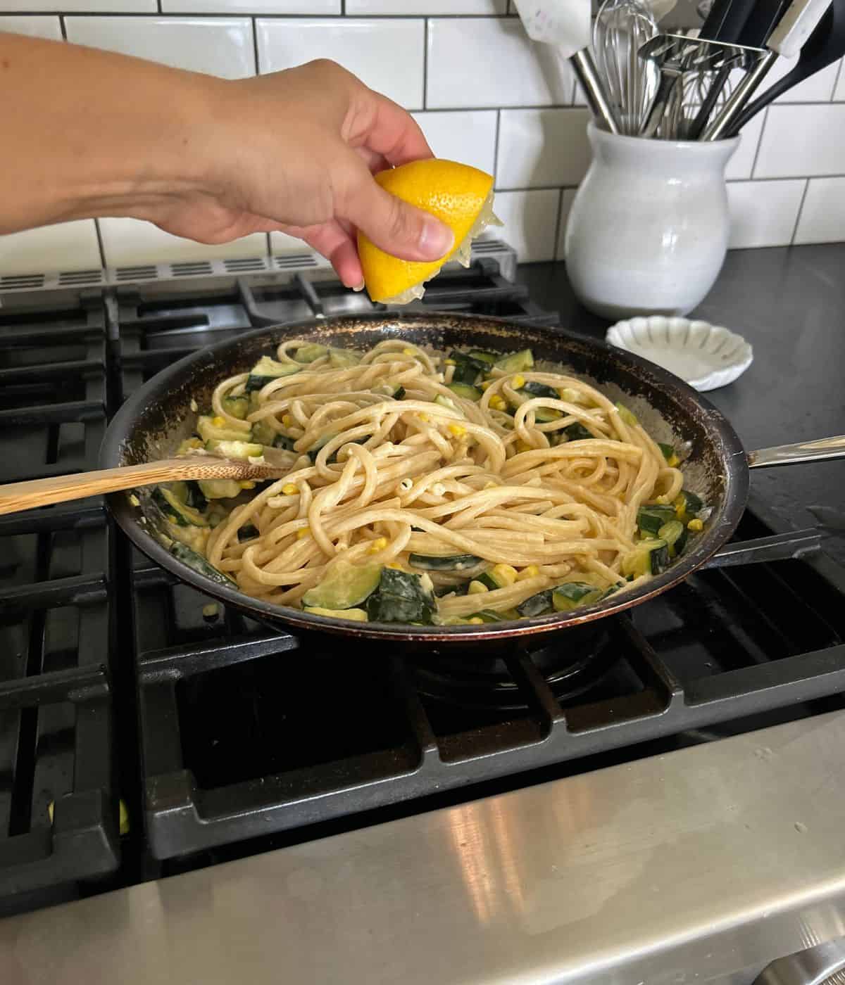 Squeezing lemon over pasta.