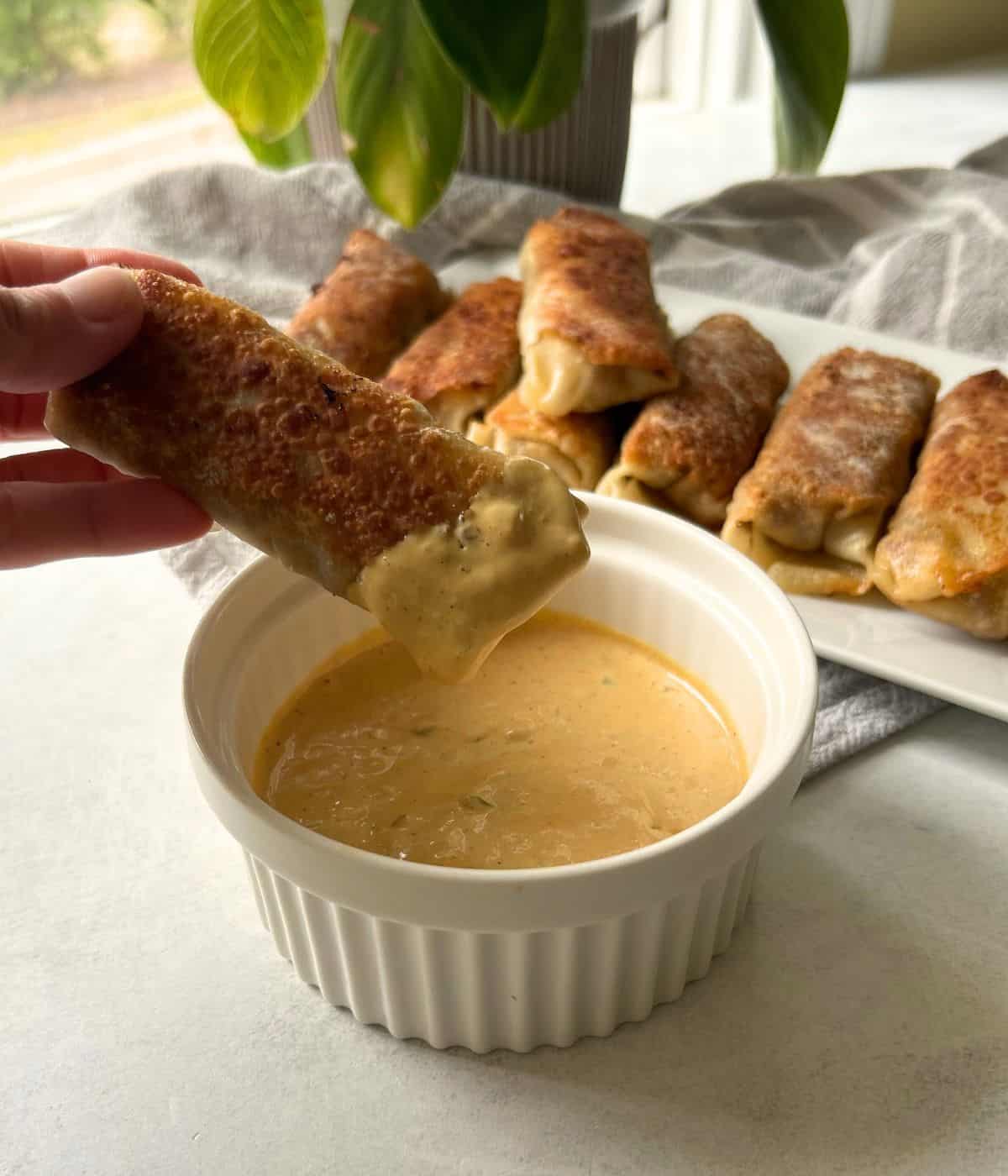 Cheeseburger egg roll dipped in sauce.