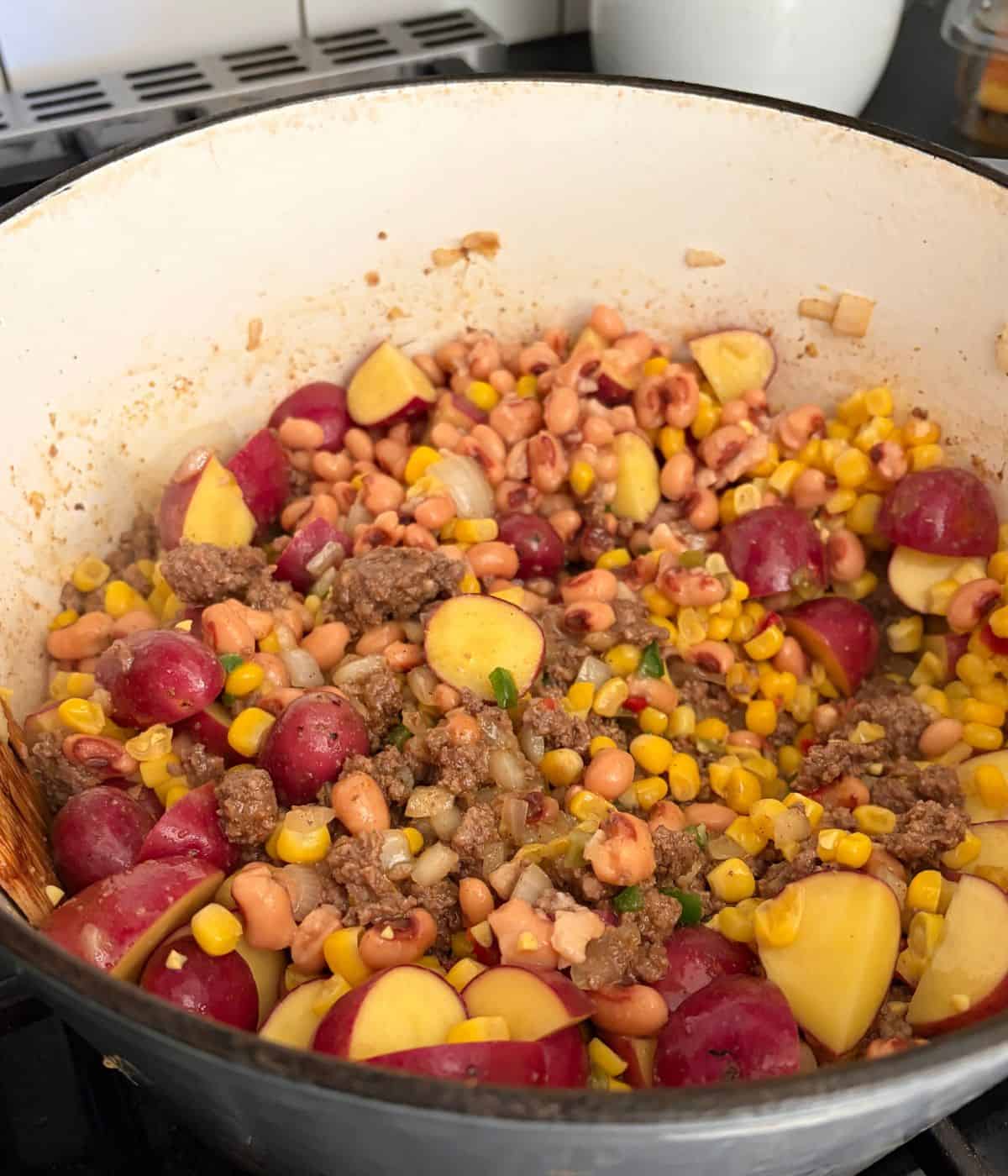 Potatoes, corn, and beef in pot.